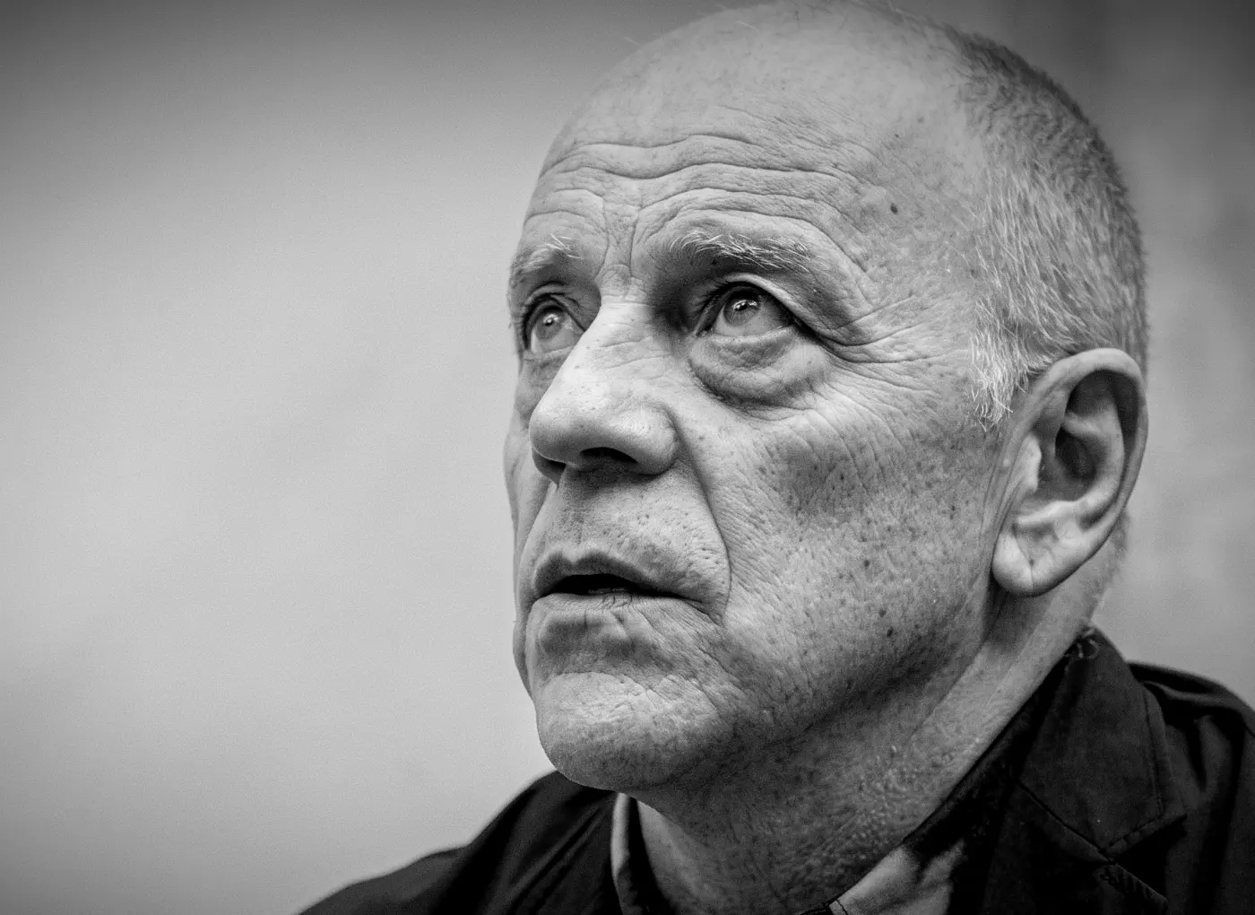 Close-up portrait of an elderly man looking upward with a contemplative expression in black and white