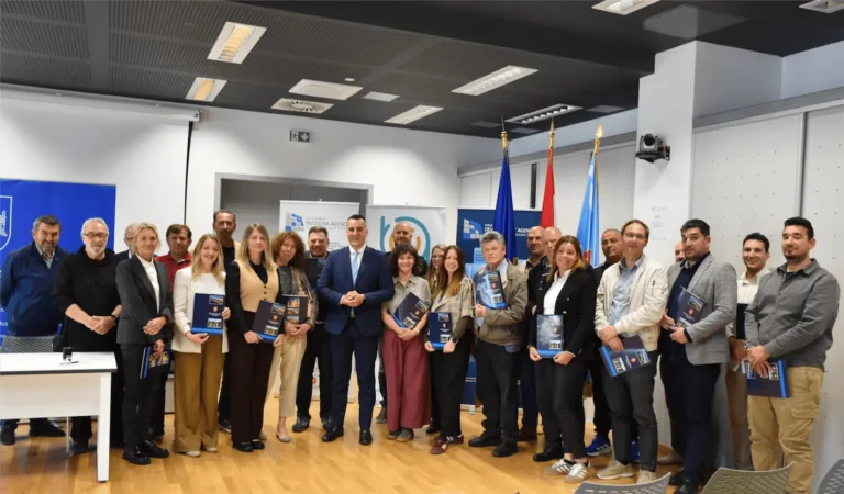 Group of professionals in a conference room posing with blue booklets during a ceremony.