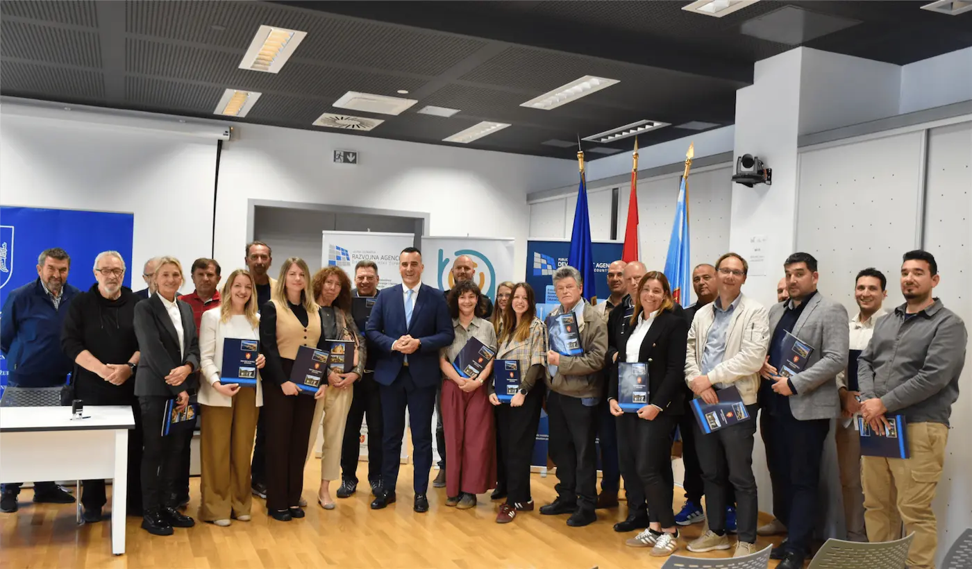 Group of professionals in a conference room posing with blue booklets during a ceremony.