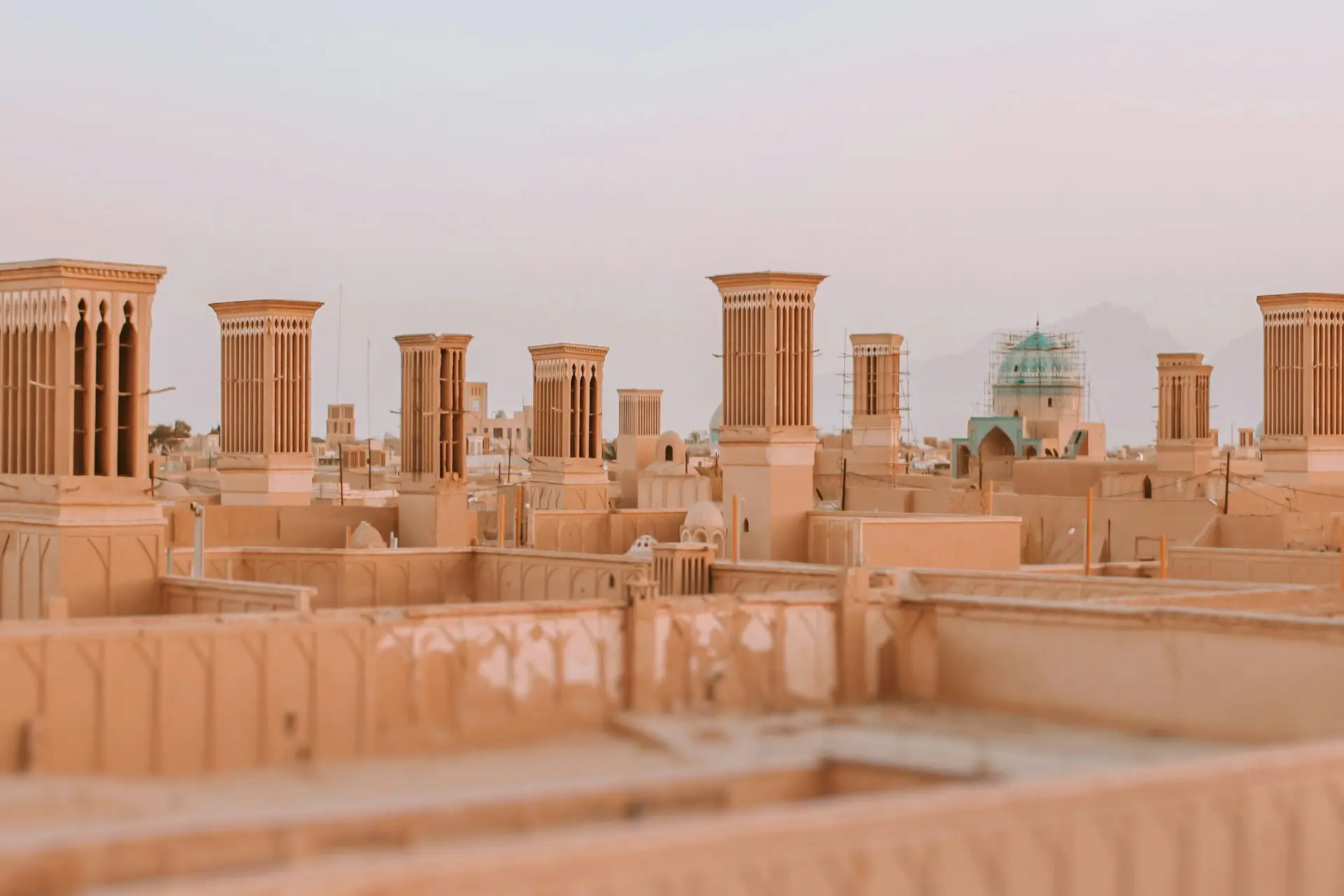 Rooftop cityscape with traditional wind towers (barjeel) on beige buildings at sunset.