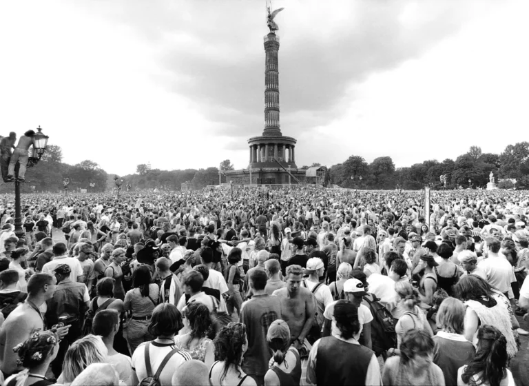 Large crowd gathered in front of the Berlin Victory Column during an outdoor festival or event, with the monument rising in the center and trees in the background.