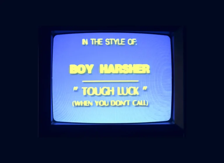 CRT television displaying a blue title card with yellow stylized text: "IN THE STYLE OF" then "BOY HARSHER" underlined, followed by "TOUGH LUCK" and a parenthetical note "(WHEN YOU DON'T CALL)".
