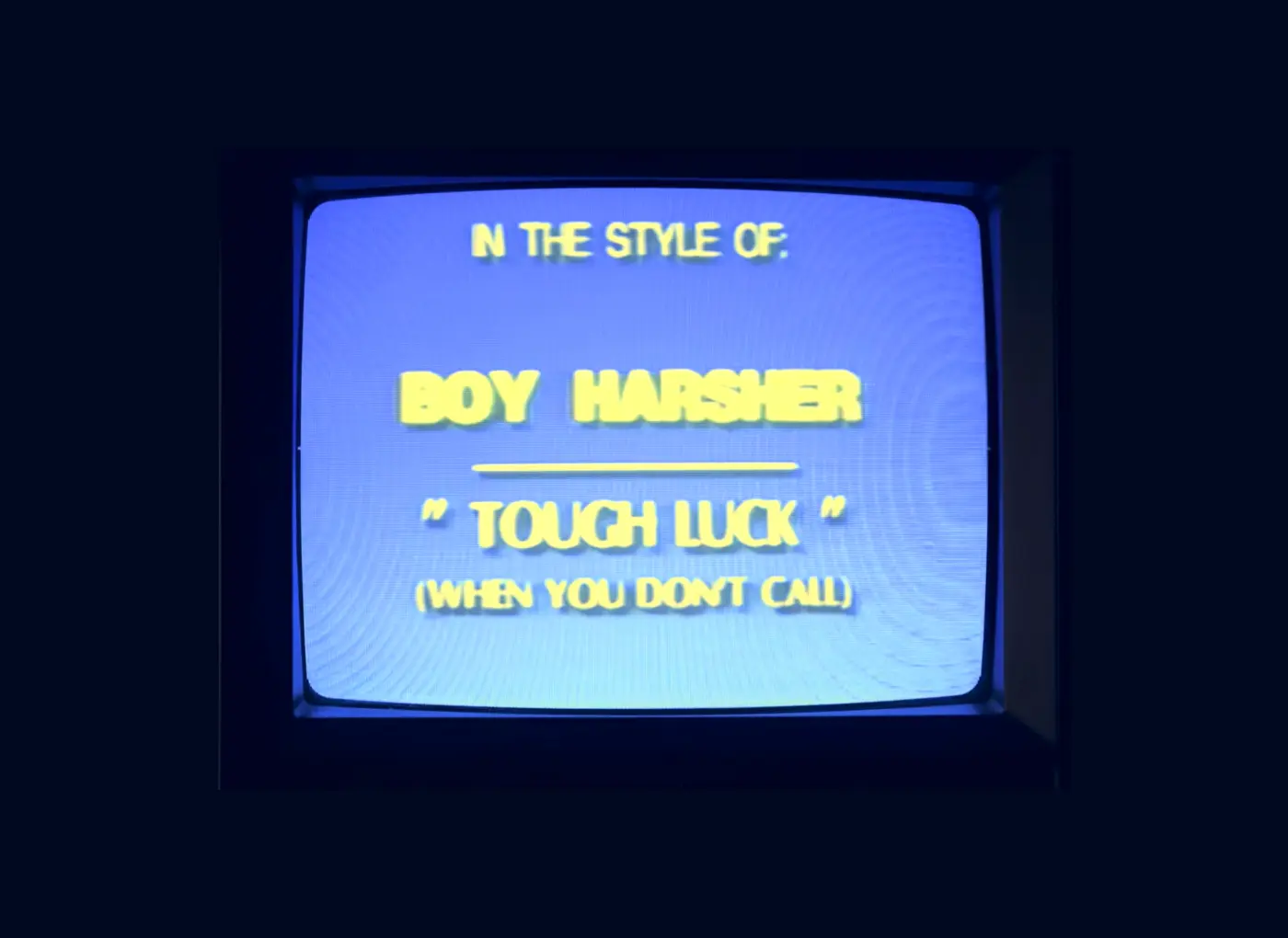 CRT television displaying a blue title card with yellow stylized text: "IN THE STYLE OF" then "BOY HARSHER" underlined, followed by "TOUGH LUCK" and a parenthetical note "(WHEN YOU DON'T CALL)".