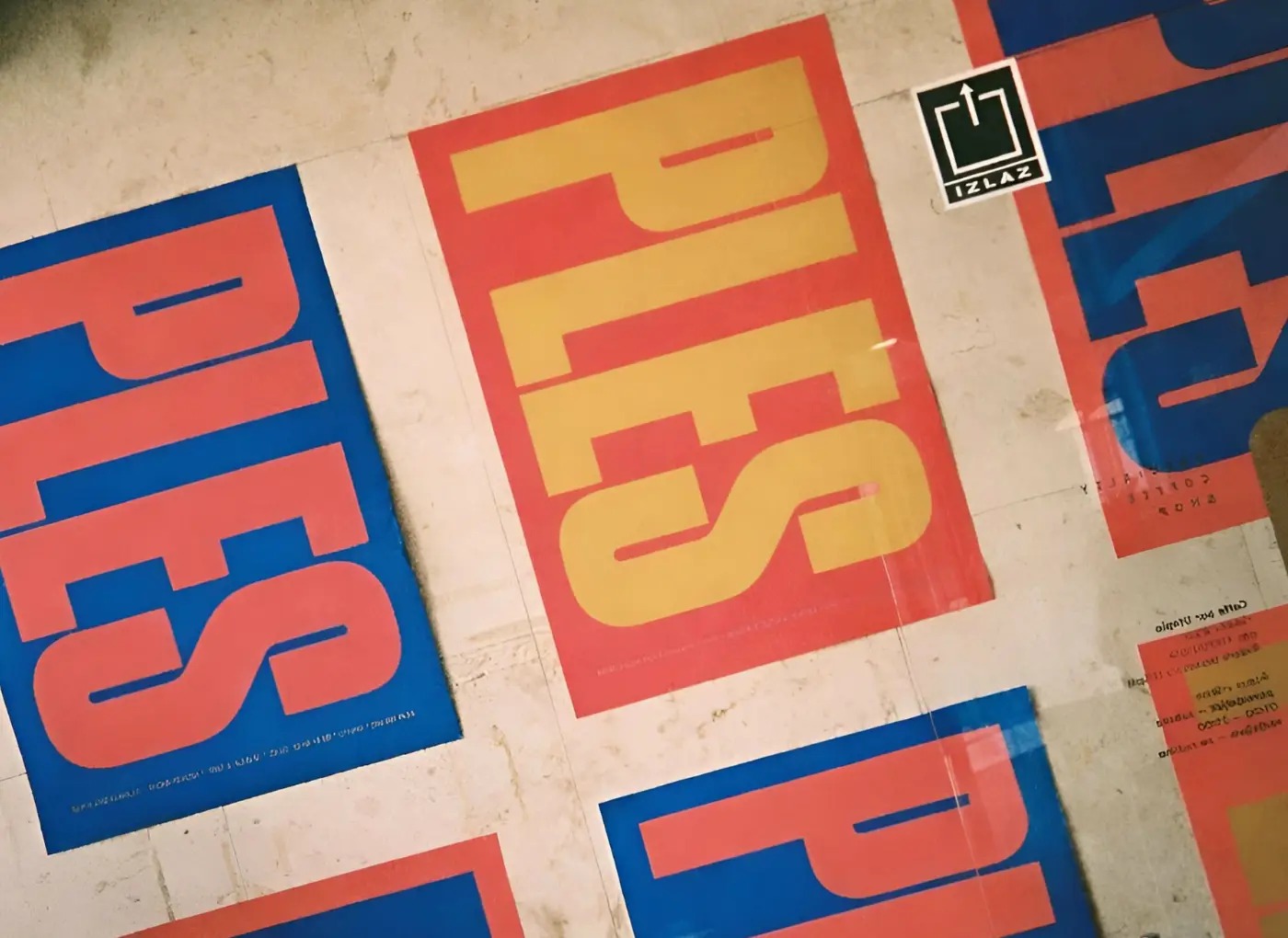 Abstract wall art with large orange-yellow letters on red panels, set against blue and light backgrounds.