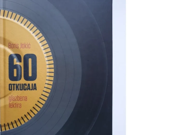 Close-up of a yellow circular dial with the number 60 and the name Boris Jokić on a dark surface.--